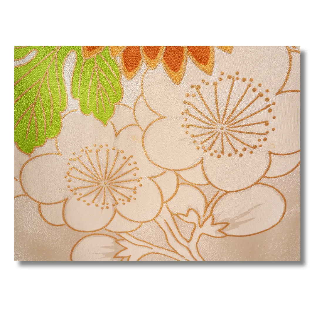 Detailaufnahme grüner Blätter und Blütenmotive auf cremefarbenem Furisode-Stoff