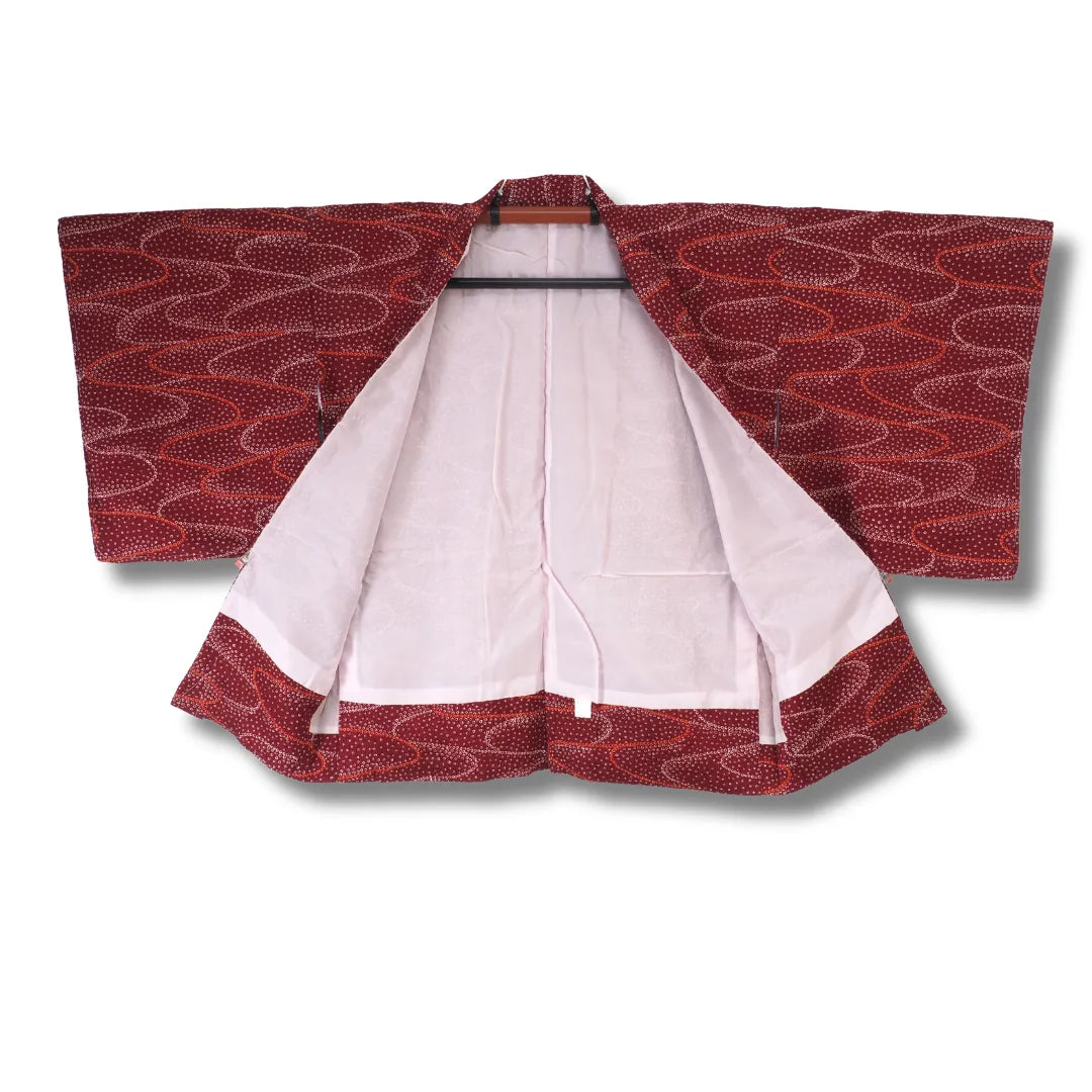 Dunkelroter Shibori-Haori aufgehängt, cremeweißes Futter im Kontrast sichtbar