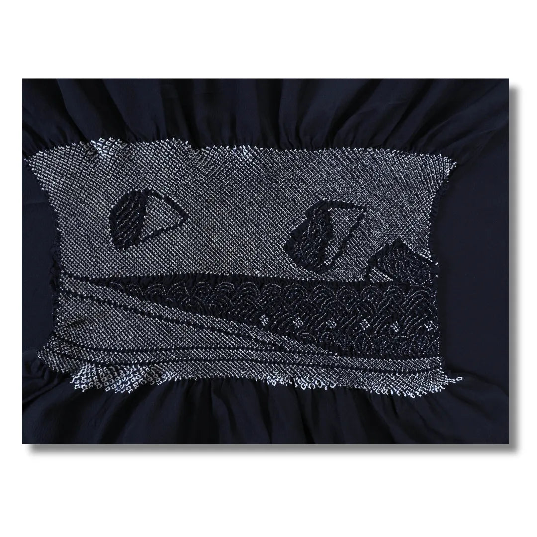 Seigaiha-Wellenbögen und dunkle Formen im Shibori auf tiefblauem Stoff