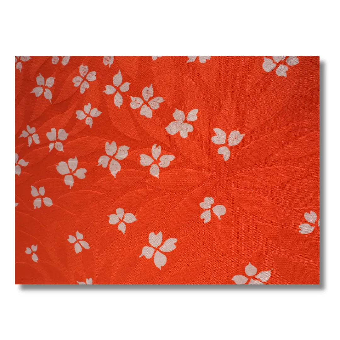 Stoffdetail mit weißen Blumenmustern auf orangem Hintergrund