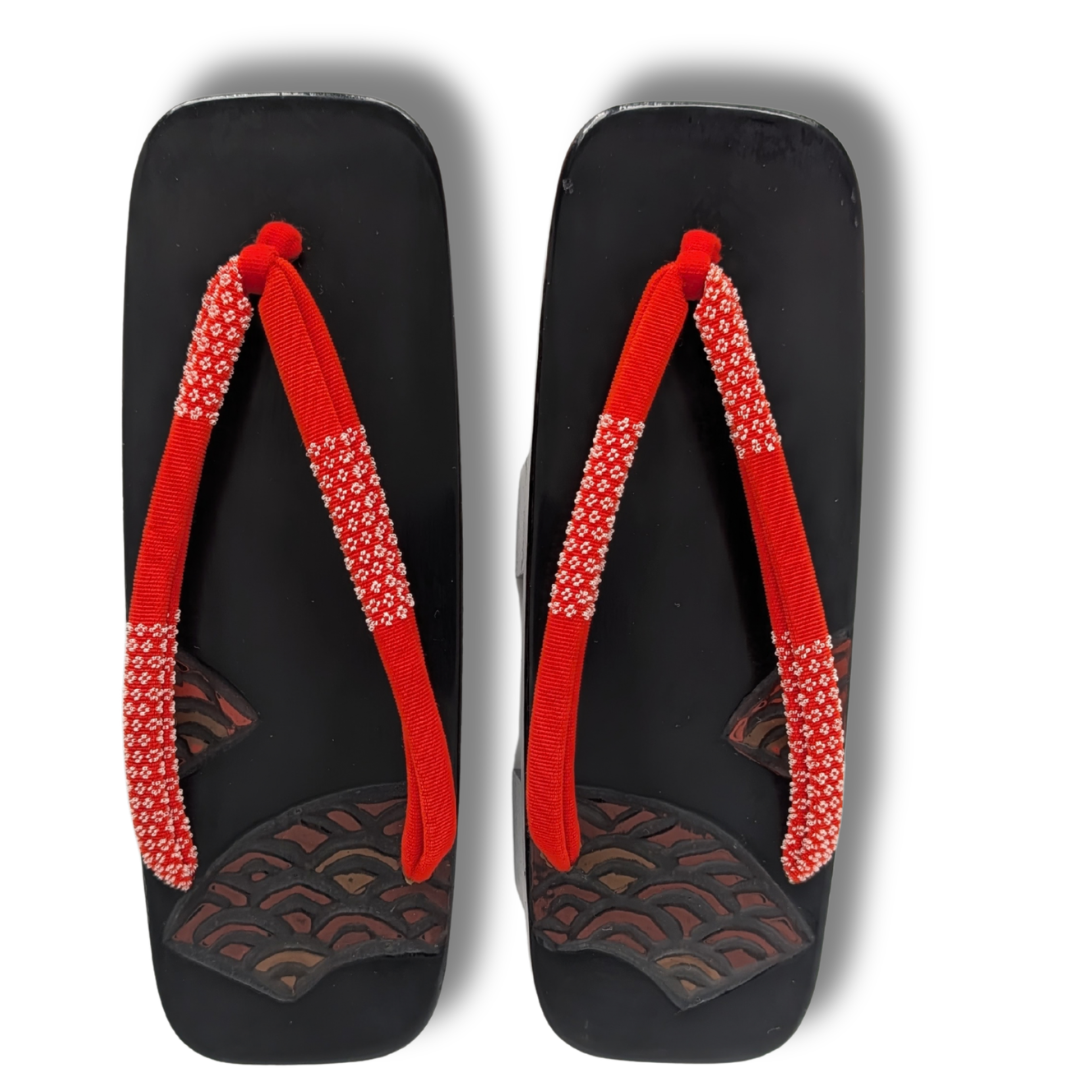 Vintage Damen Geta aus Holz in Schwarz mit roten Hanao und weißen Details sowie traditionellem Wellenmuster auf der Oberfläche