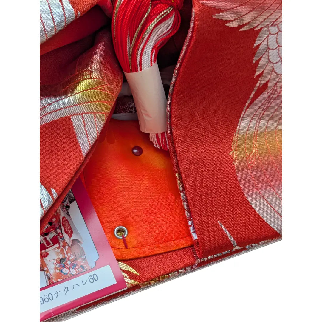Detail Vintage Musubi Obi Schleife in Rot mit Kranich-Muster und dekorativen Kordeln.