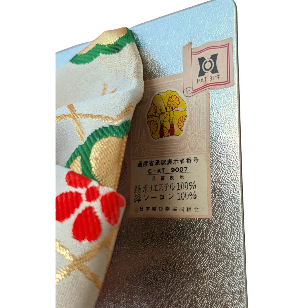 Etikett Vintage Musubi Obi Schleife in Weiß mit roten Kordeln und traditionellen Blumenmustern.