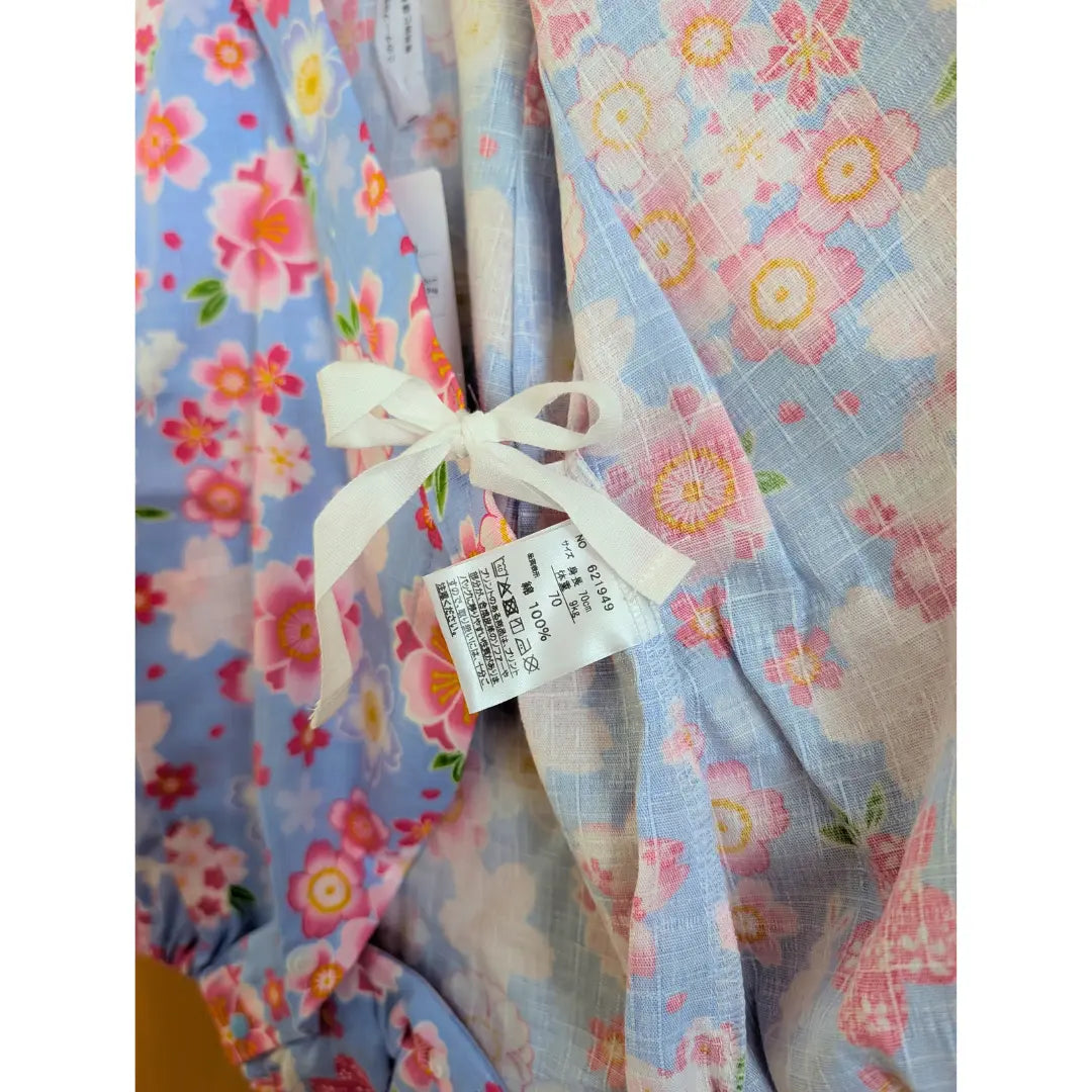 Innenansicht des hellblauen Baby Kimono Bodys mit Sakura Kirschblüten, Häschen, weißer Bindeschleife und Materialetikett aus Japan.