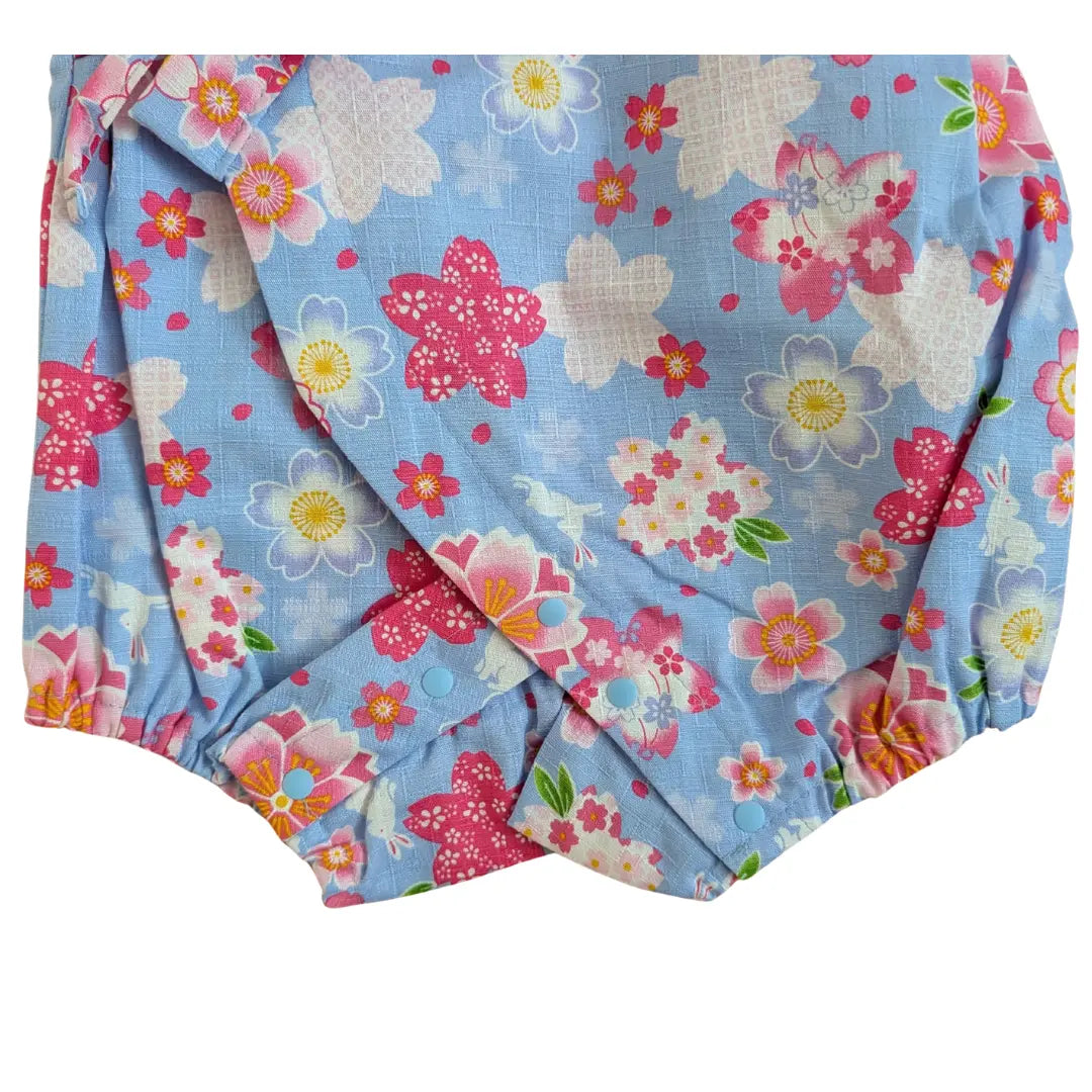 Nahaufnahme des unteren Bereichs des japanischen Baby Kimono Bodys mit Sakura Muster, elastischen Beinabschlüssen und hellblauen Druckknöpfen im Schritt.