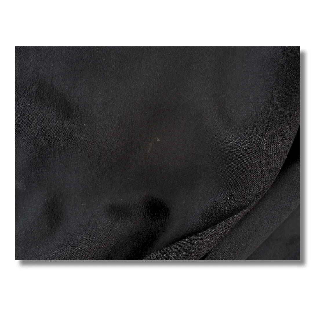 Faltiger schwarzer Stoff mit feinem Fleck im Detail