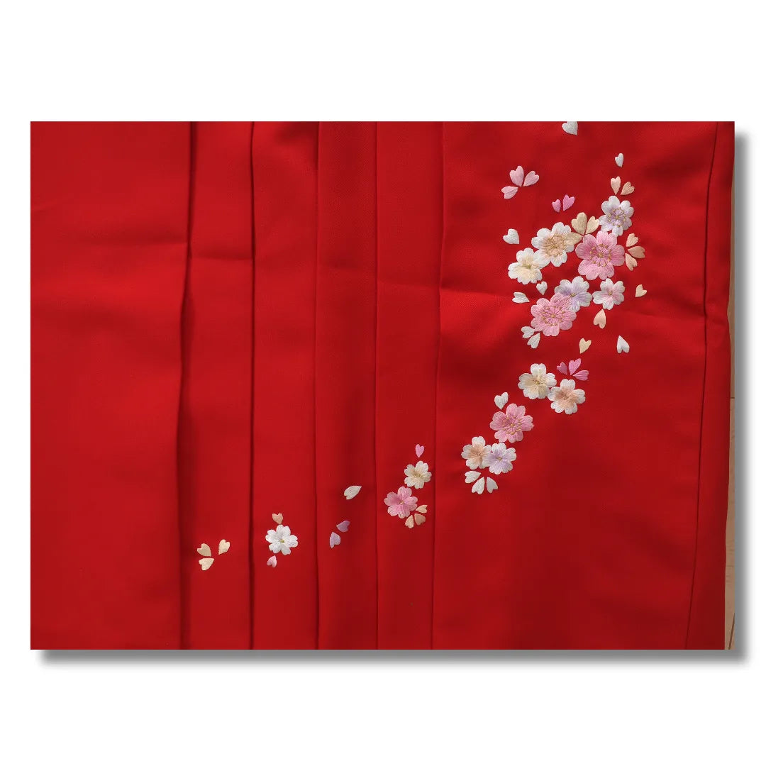 Gestickte Kirschblüten auf den Plisseefalten des roten Hakama