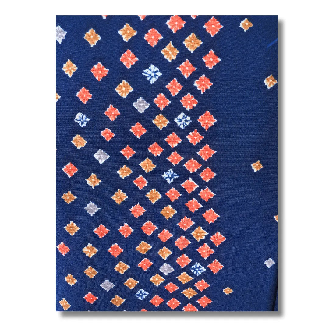 Großformatige Nahaufnahme des Rautenmusters in Korall und Orange auf dunkelblauem Polyester