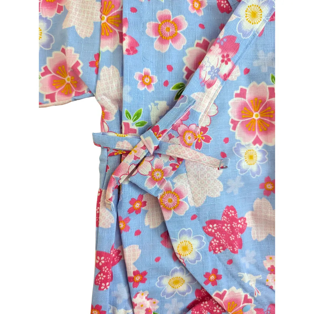 Detailaufnahme der seitlichen Stoffbindung am hellblauen Baby Kimono Body mit rosa Sakura Kirschblüten und traditioneller Wickeloptik.