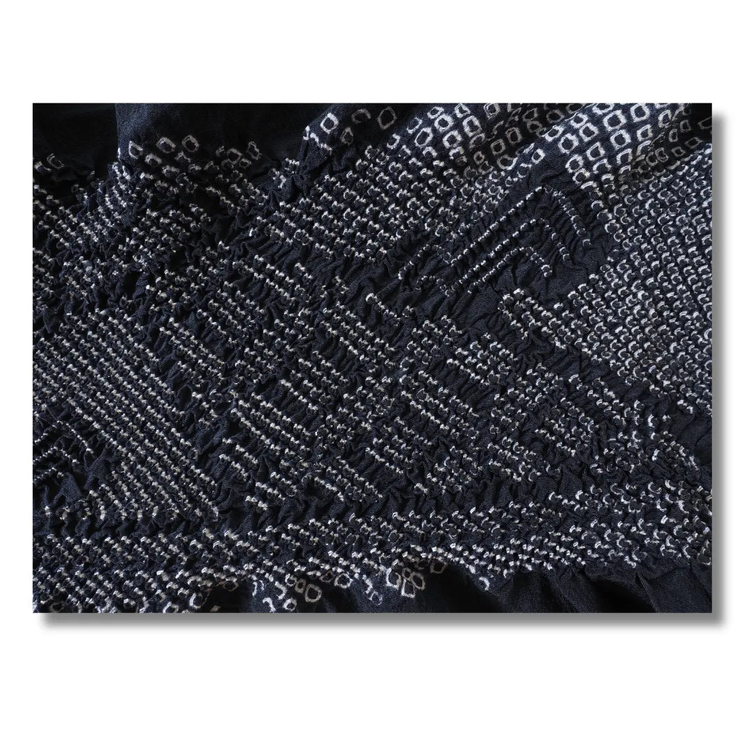Makroaufnahme der geometrischen Shibori-Formen in Weiß auf Dunkelblau
