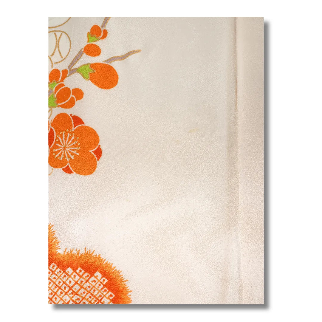 Nahaufnahme einer orangefarbenen Chrysanthemenblüte auf cremefarbenem Furisode-Stoff