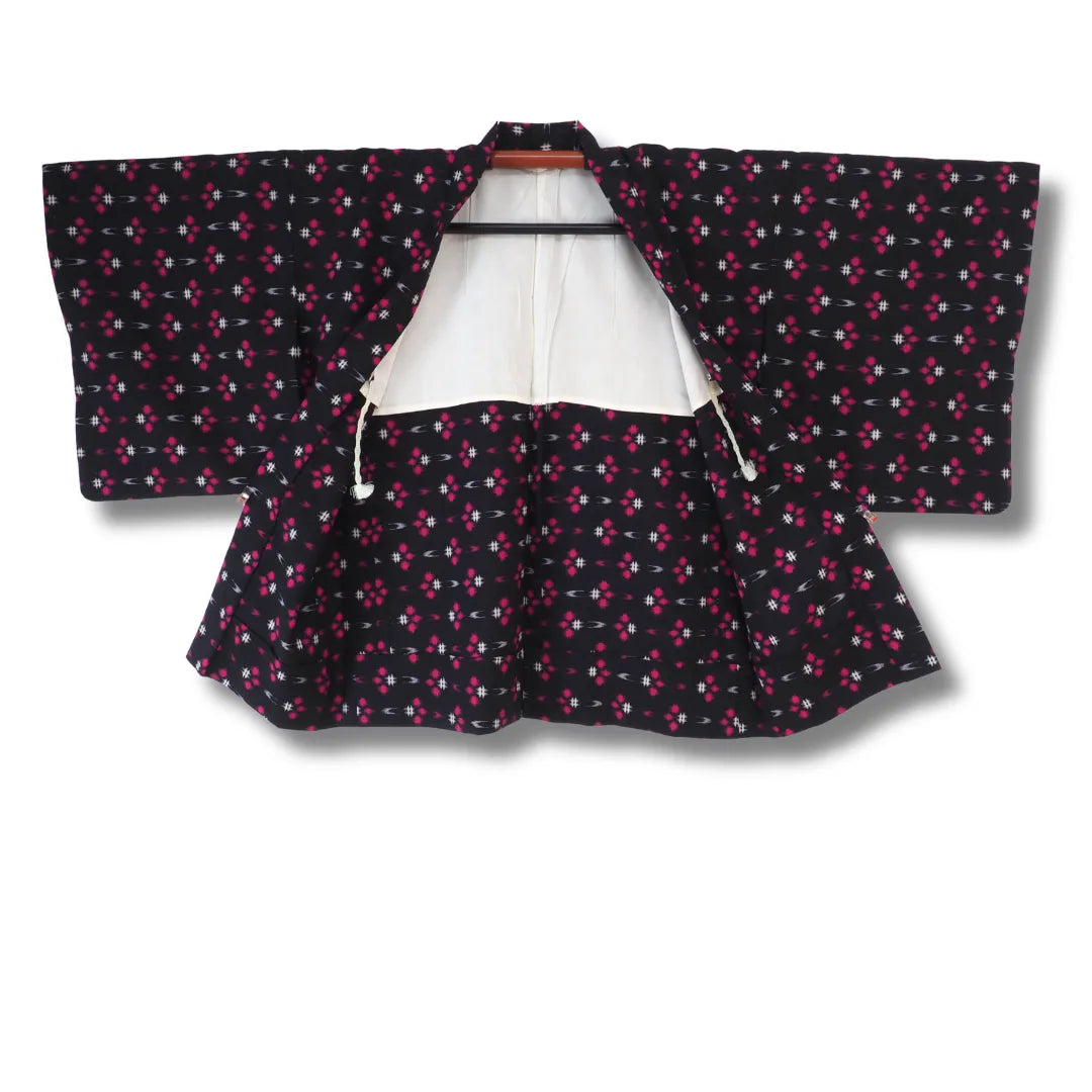 Schwarzer Haori aufgehängt, weißes Futter und durchgehendes Muster sichtbar