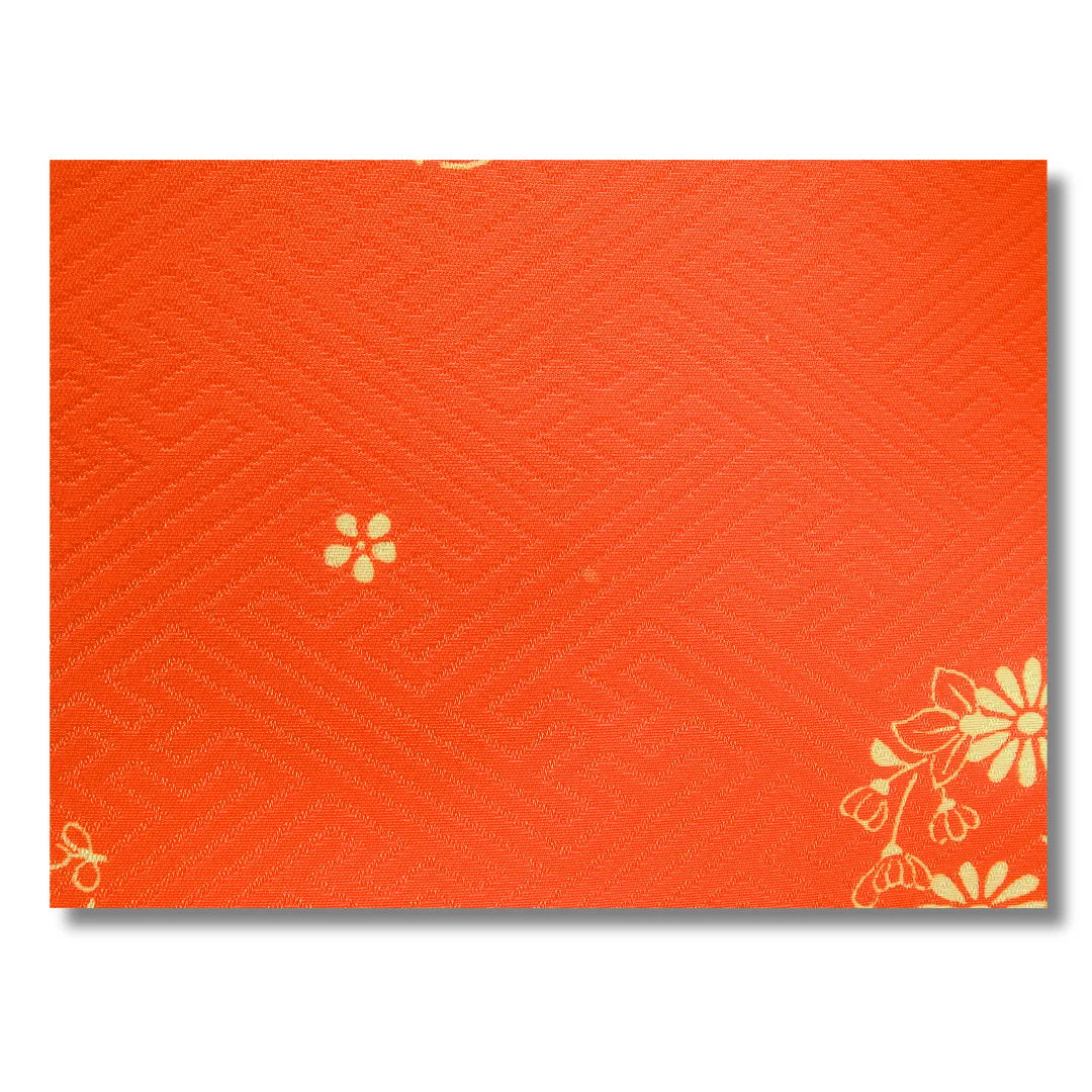 Nahaufnahme des orangefarbenen Stoffes mit kleiner Blüte und Sayagata Musten mit winzigem Fleck