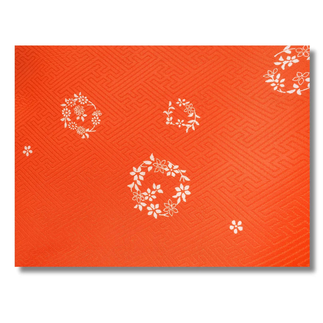Detailaufnahme des floralen Musters auf orangefarbenem Stoff