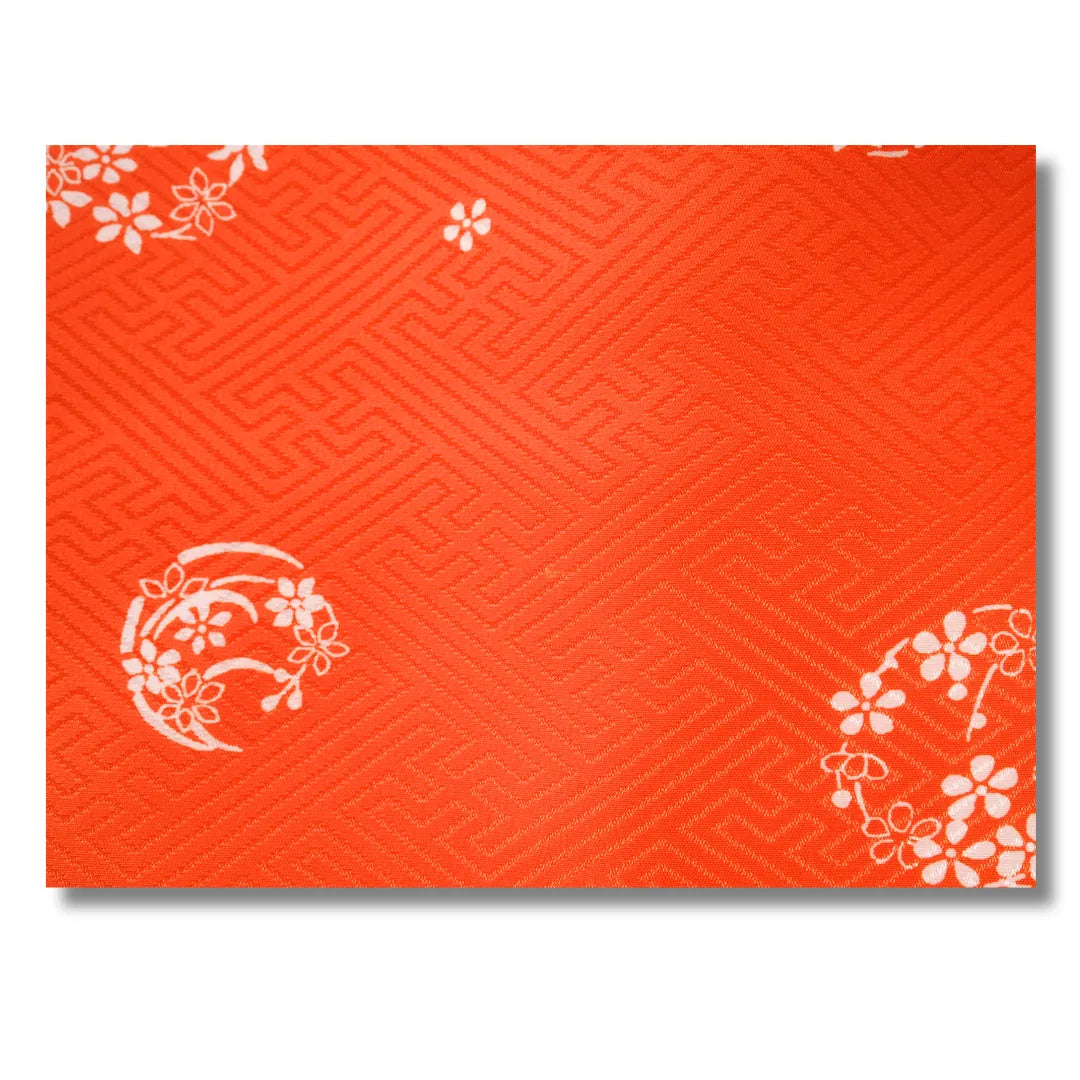 Stoffdetail mit weißen Blumenmotiven auf Orange