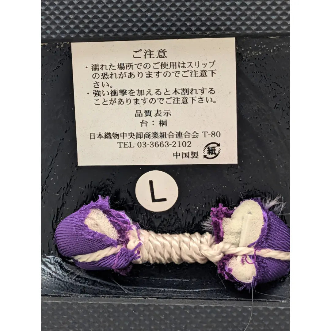 Detailaufnahme der traditionellen Befestigung japanischer Geta mit lila Hanao-Riemen