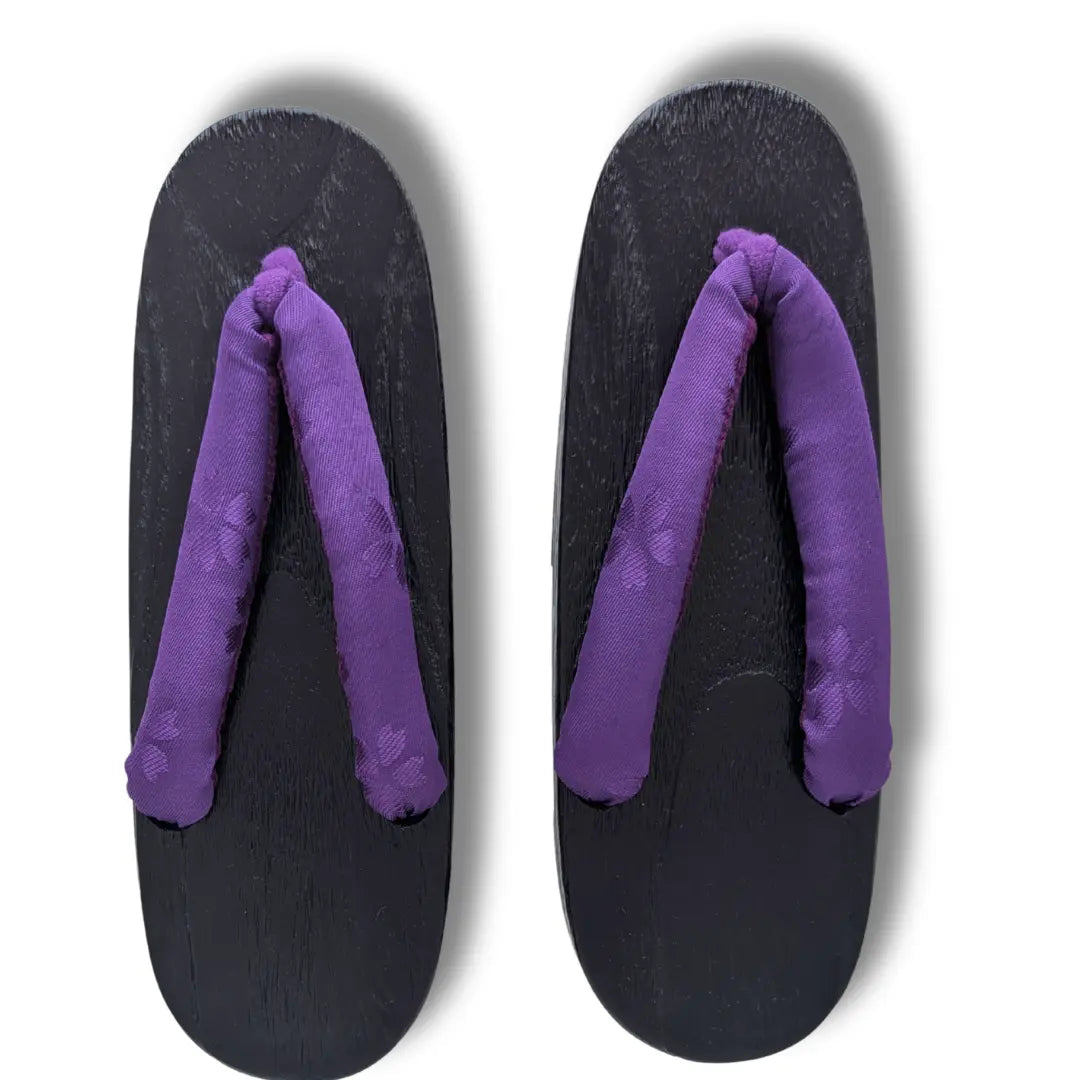 Traditionelle japanische Holzsandalen mit lila Kirschblüten-Riemen und schwarzem Holzdesign