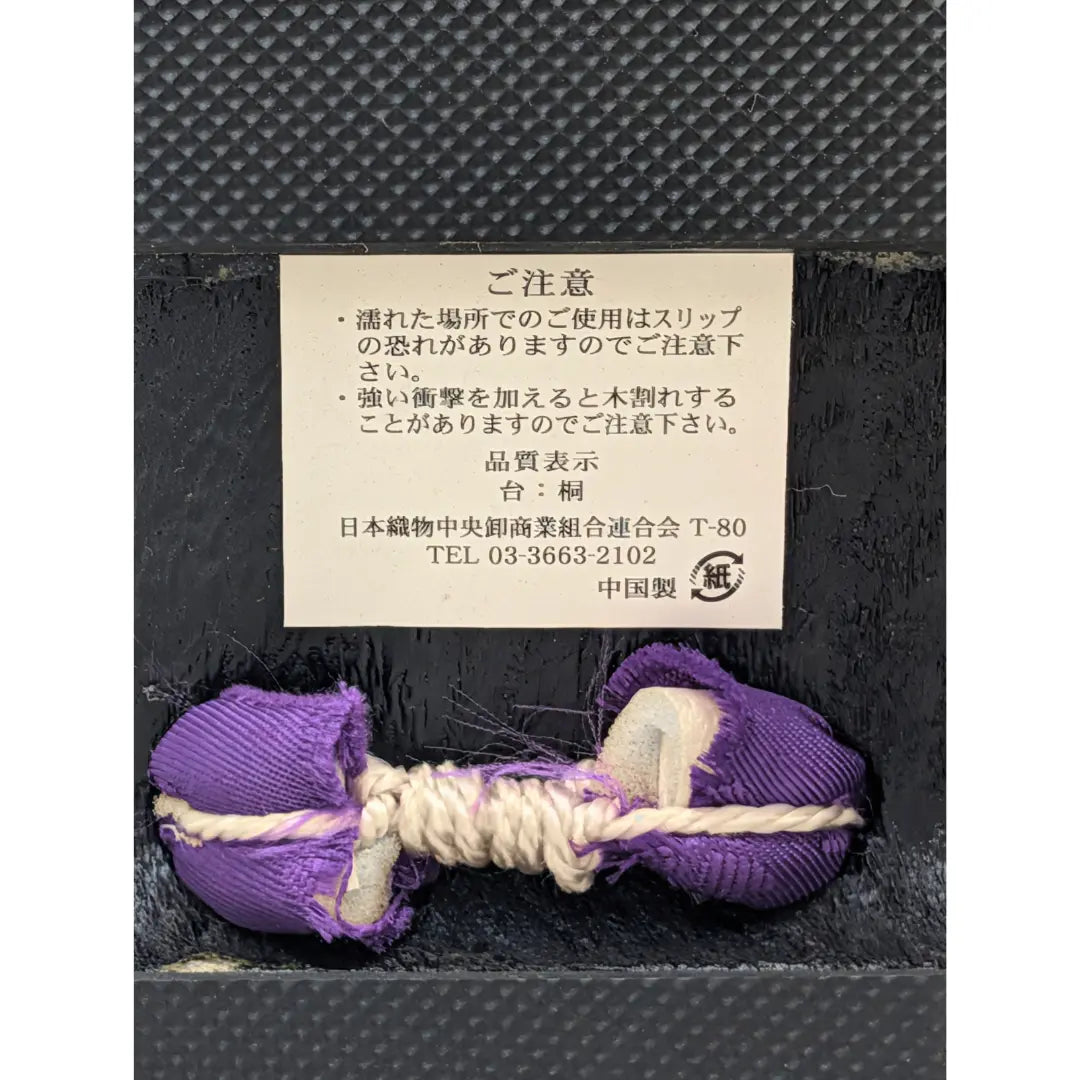 Detailaufnahme der traditionellen Geta Sandalen aus Holz mit lila Hanao Riemen und japanischem Etikett