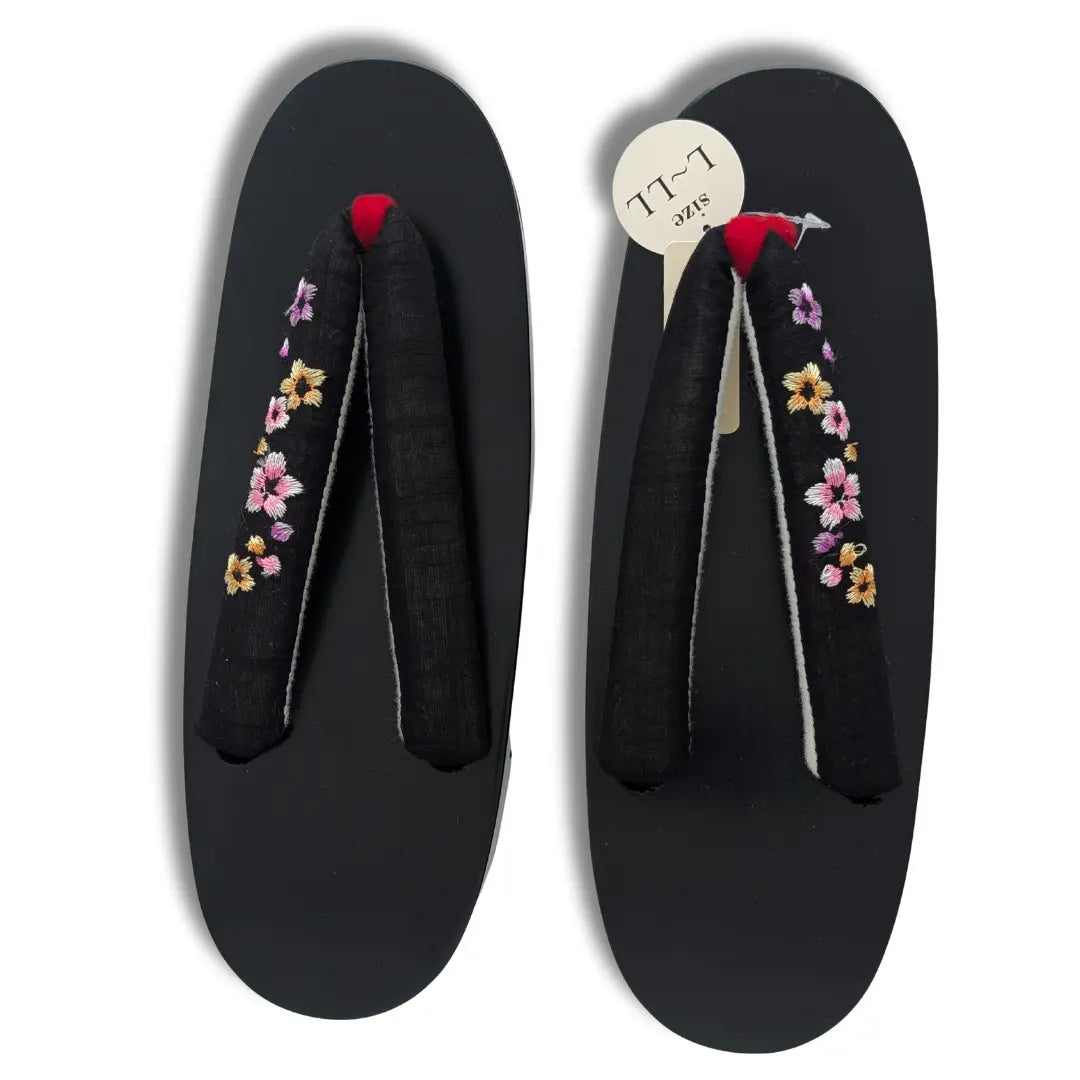 Traditionelle schwarze Geta aus Holz mit bestickten Sakura-Blüten und rotem Zehensteg
