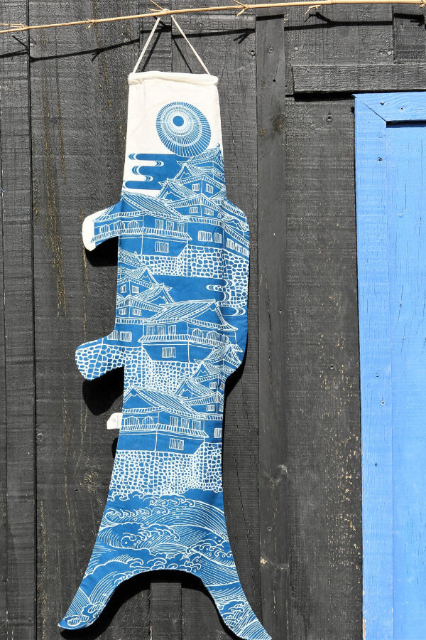 Koinobori Größe M Ôshiro in Blau hängt an einer braunen Holzwand #farbe_Blau