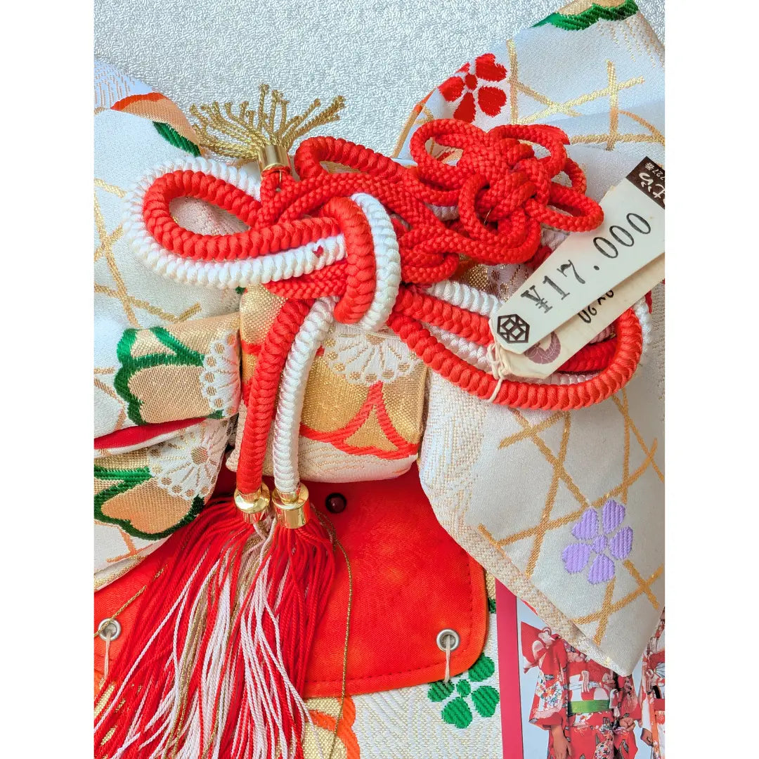 Quasten Vintage Musubi Obi Schleife in Weiß mit roten Kordeln und traditionellen Blumenmustern.